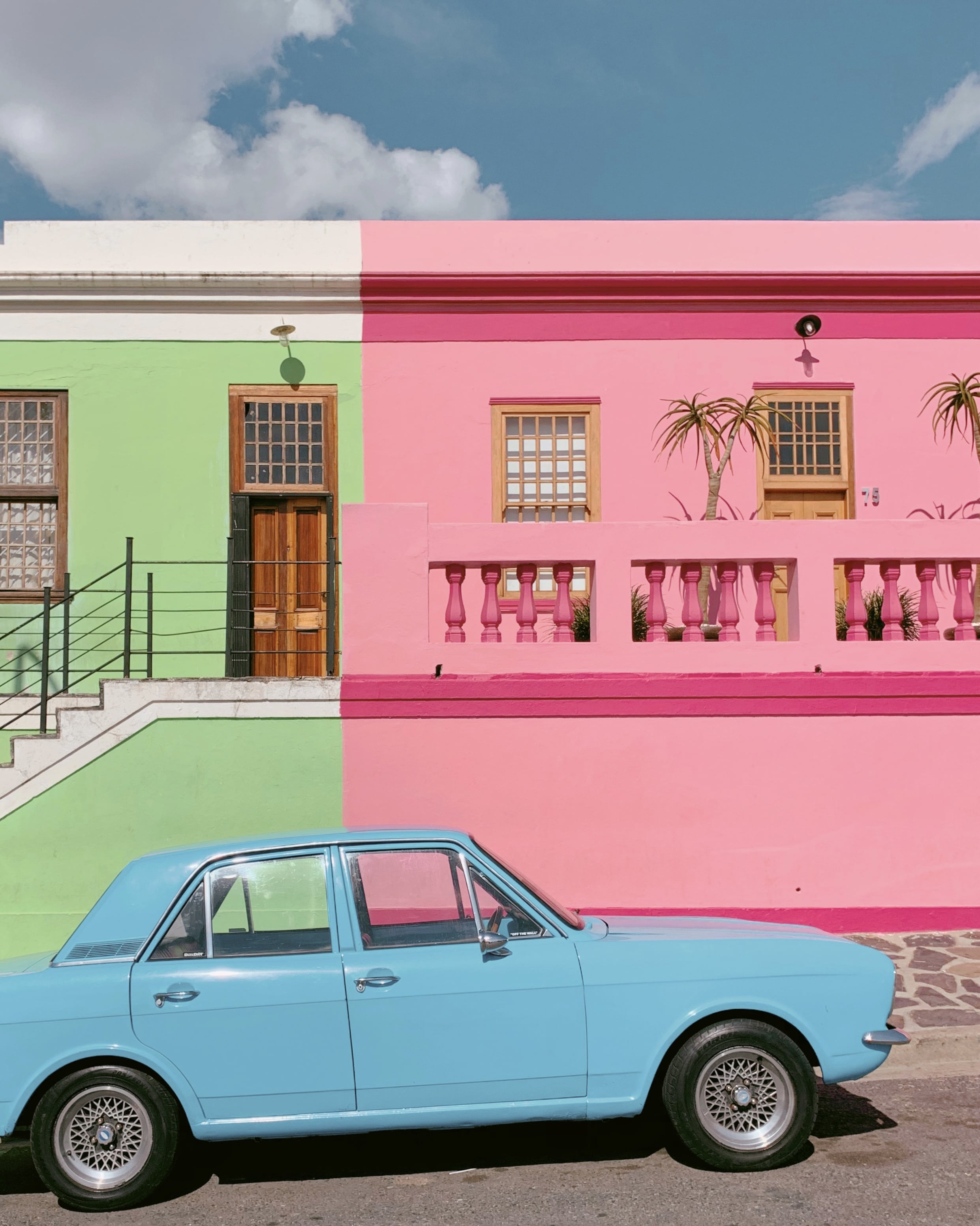 blue car in front of green and pink wall