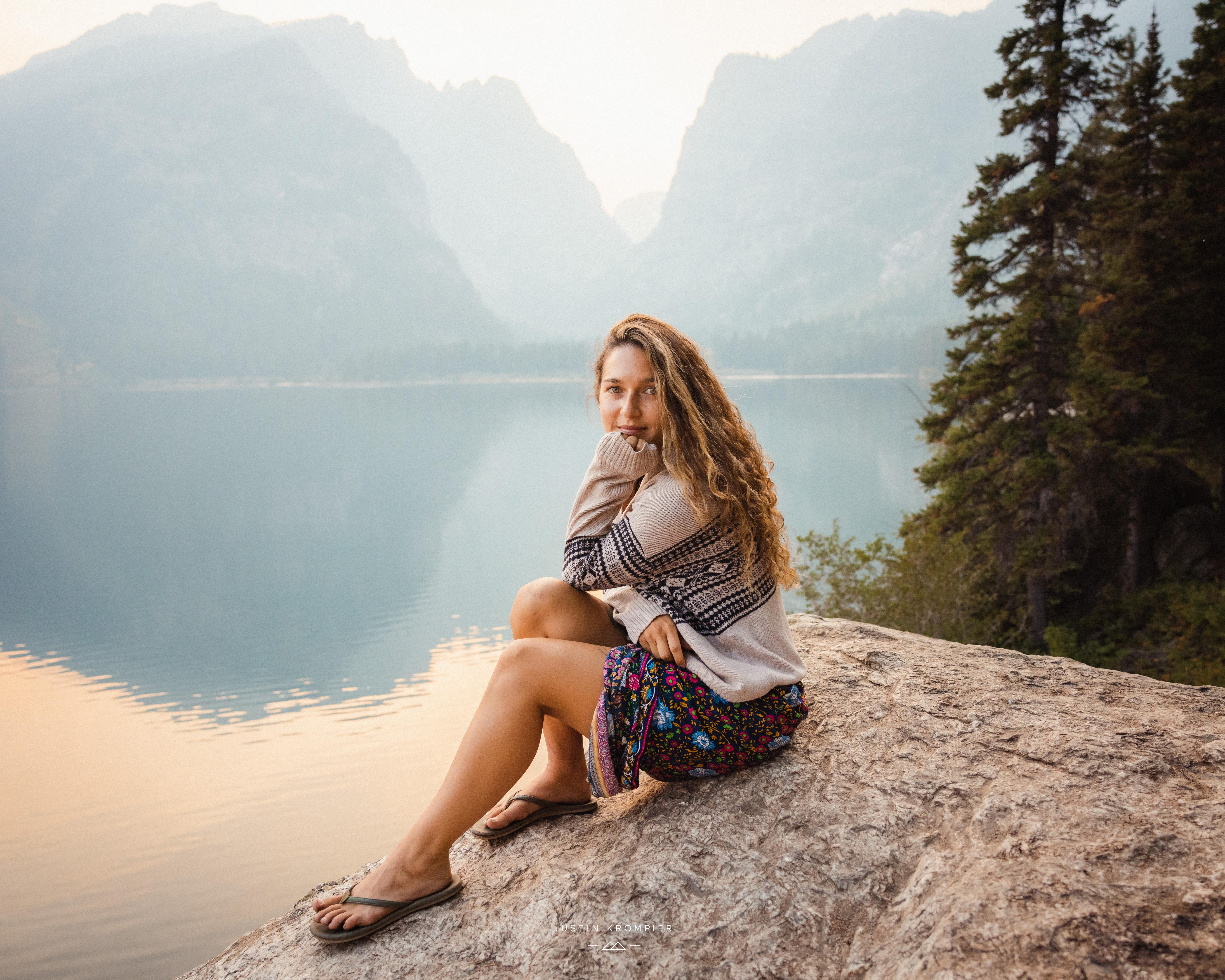 Woman sitting on a rock with mountainscape backdrop