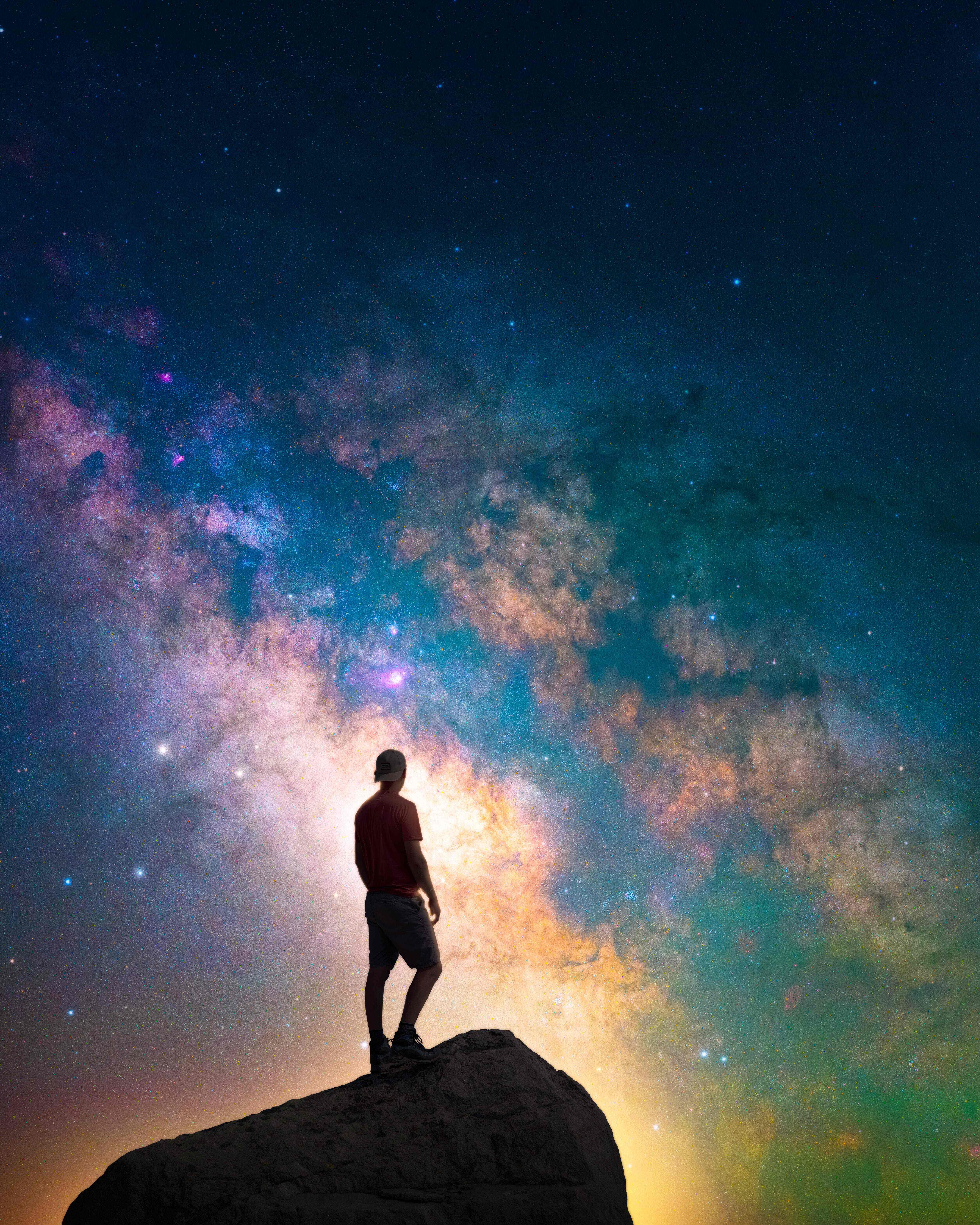 Man facing galaxy background on top of mountain
