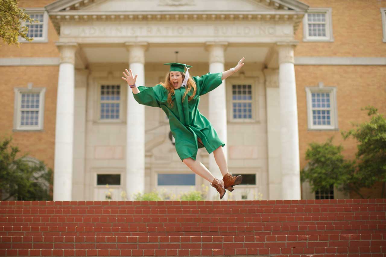 Graduate jumping in photo wearing green robe