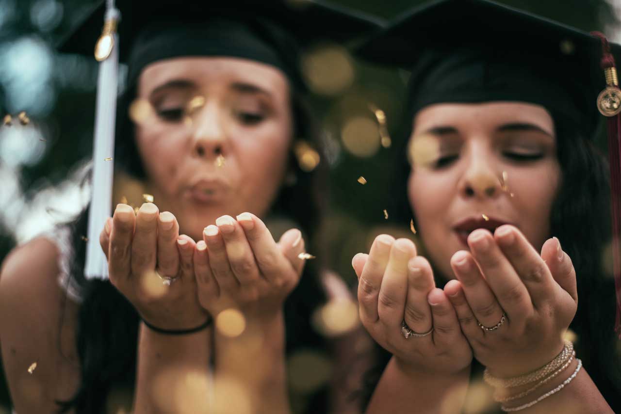 Graduates blowing glitter for graduation photos