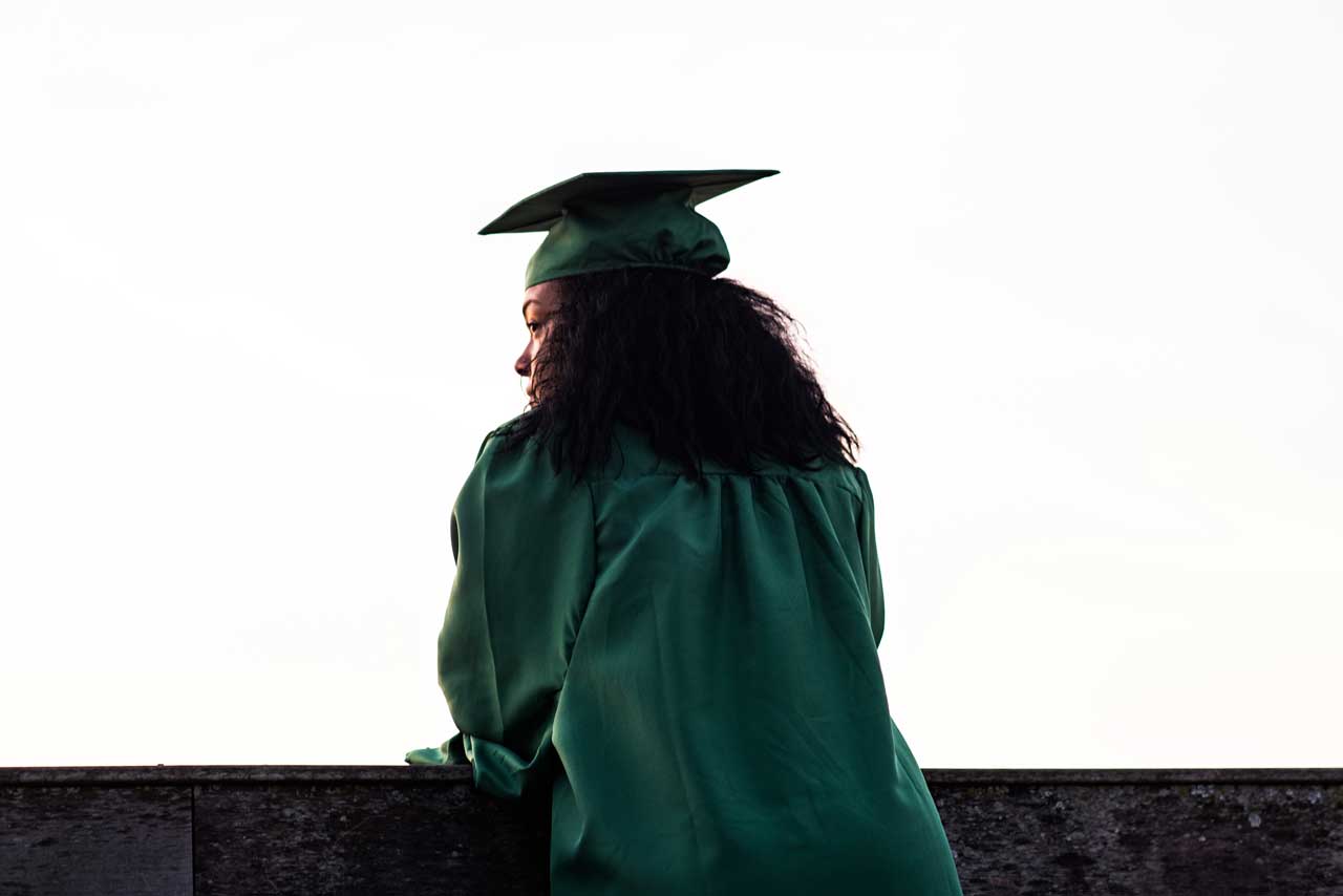 Girl wearing green cap and gown for graduate photos
